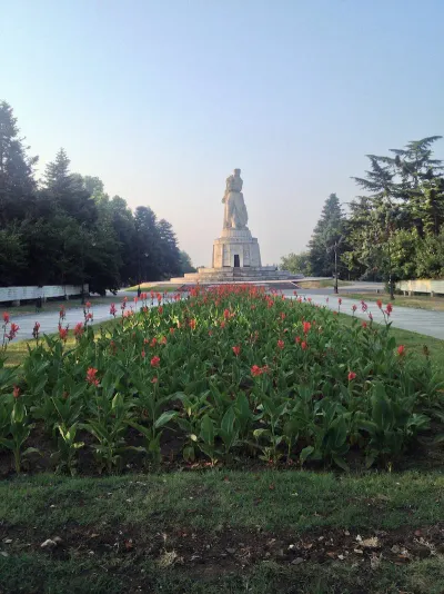 A lush green park with walking paths overlooking the sea